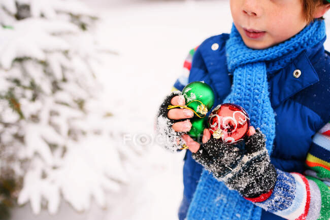 Мальчик держит рождественские украшения на улице — стоковое фото
