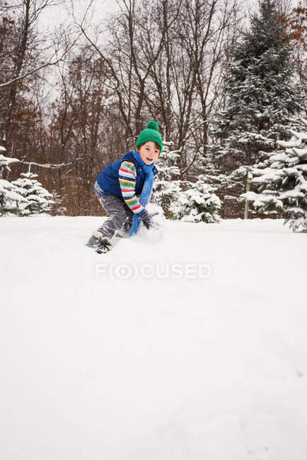 Boy Making sosteniendo una bola de nieve gigante - foto de stock