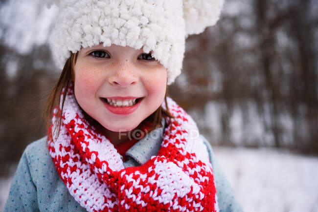 Retrato de uma menina sorridente em um chapéu bobble na neve — Fotografia de Stock