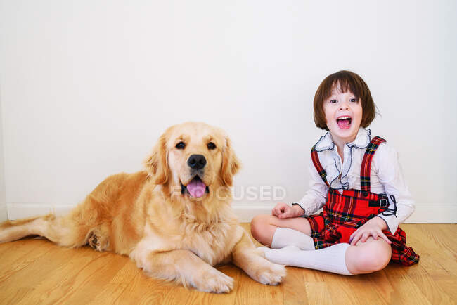 Menina sentada no chão com seu cão golden retriever — Fotografia de Stock