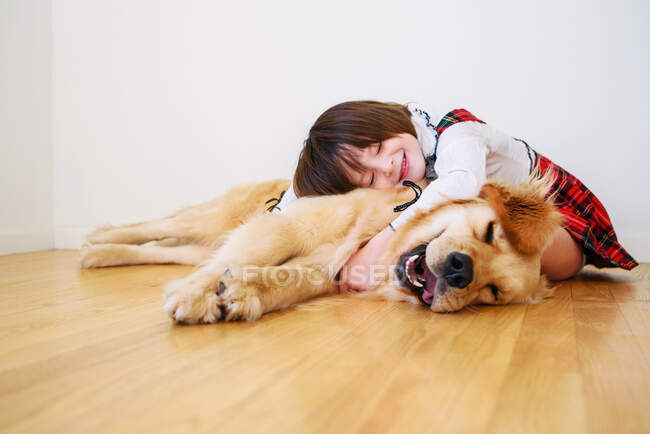 Девушка сидит на полу и обнимает свою собаку. — стоковое фото