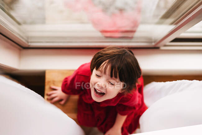 Blick von oben auf ein Mädchen, das an einem Vorhang sitzt und lacht — Stockfoto