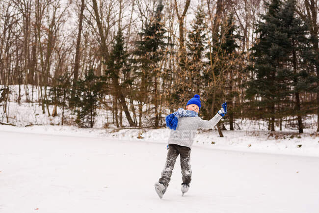 Boy learning to ice skate in winter forest — Stock Photo