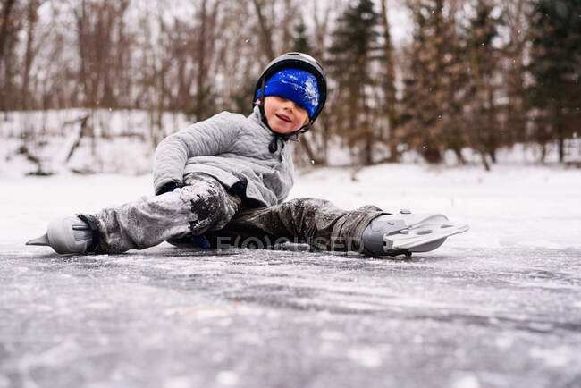 Garçon patinage sur glace et tomber sur — Photo de stock