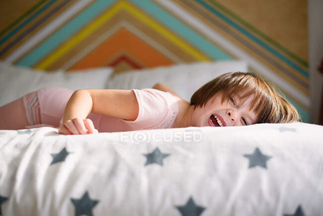 Щаслива дівчина лежить на ліжку сміється — стокове фото