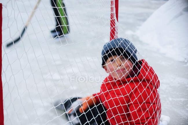 Хлопчик сидить всередині хокейної мети — стокове фото
