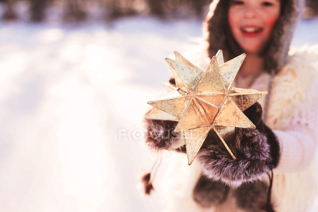 Menina em roupas quentes segurando uma estrela de ouro — Fotografia de Stock