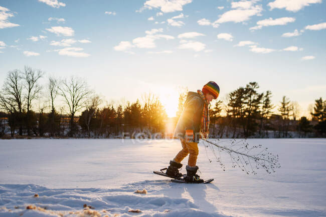 Мальчик на снегоступах на закате — стоковое фото