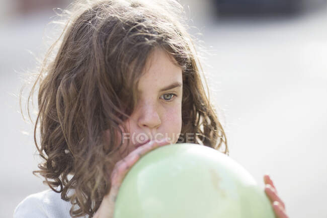 Carino ragazza soffiando su un palloncino all'aperto — Foto stock