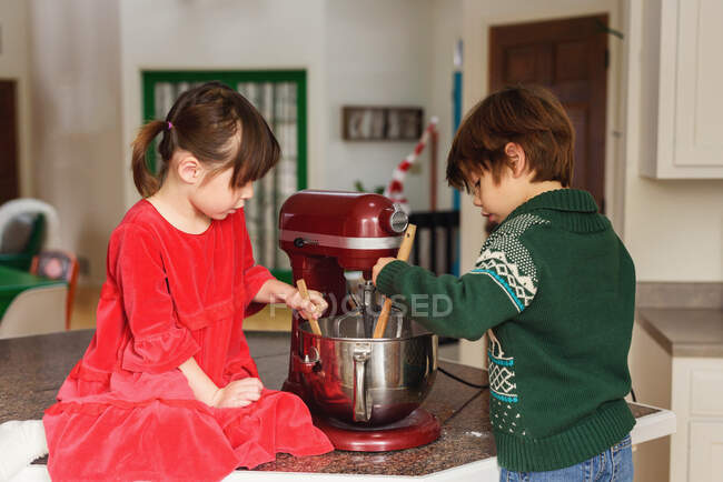 Dos niños horneando galletas en la cocina - foto de stock