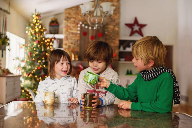 Трое детей пьют горячий шоколад на Рождество — стоковое фото