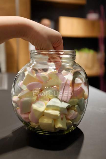 Mulher mão chegando para marshmallows em um frasco — Fotografia de Stock