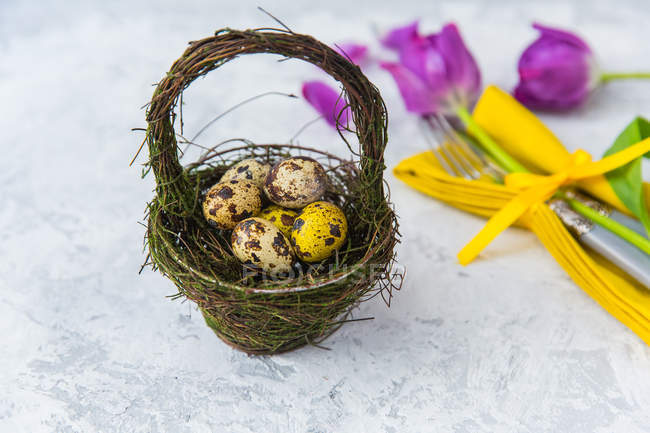 Basket with Easter eggs and place setting with flowers — Stock Photo