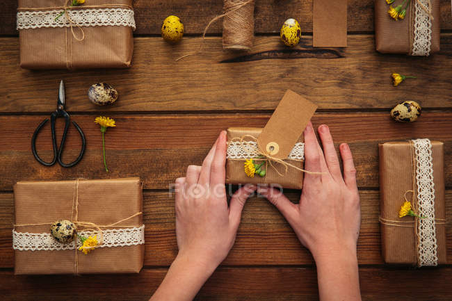 Kinderhände halten Ostergeschenk über Holztisch — Stockfoto