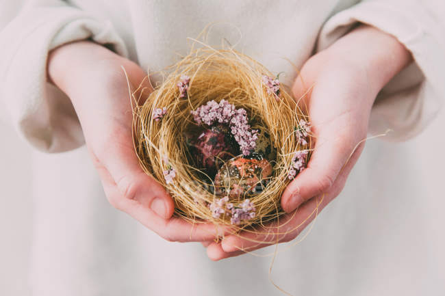 Женщина держит гнездо с пасхальными яйцами — стоковое фото
