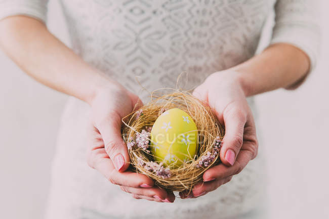 Mulher segurando um ninho com ovos de Páscoa — Fotografia de Stock
