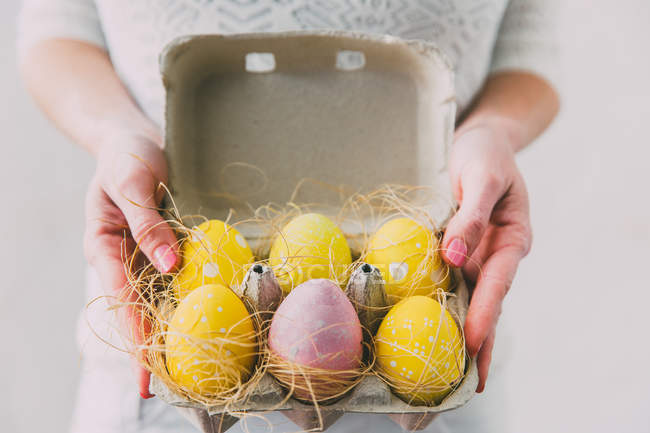 Mulher mãos segurando caixa com ovos de Páscoa pintados — Fotografia de Stock