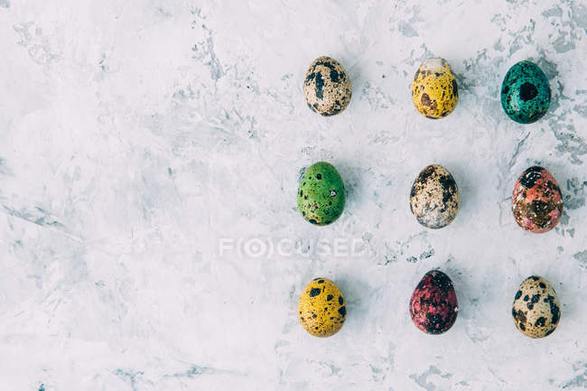 Вид зверху на різнокольорові великодні яйця над вивітрюваним фоном — стокове фото