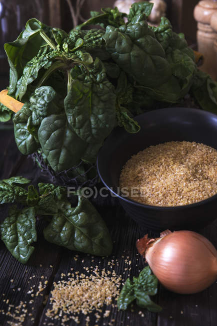 Вид крупным планом листьев шпината, сахара и лука за столом — стоковое фото
