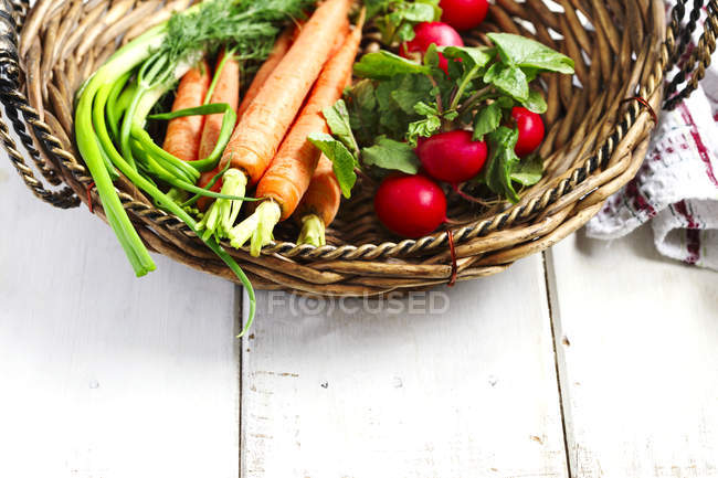 Свежие овощи в корзине над деревянным столом — стоковое фото