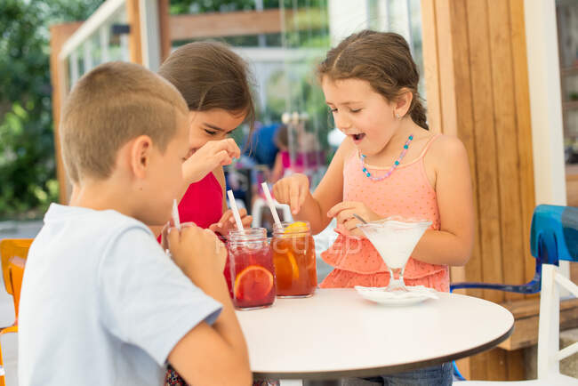 Tres niños con bebidas de té helado - foto de stock
