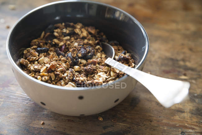 Closeup view of Bowl of granola with spoon over wooden table — Stock Photo