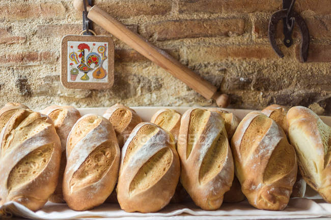 Mains de pain fraîchement préparé contre un mur de briques — Photo de stock