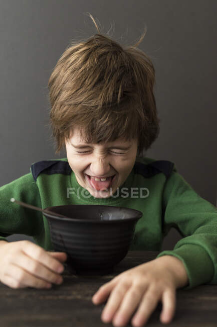 Retrato de cerca de Boy haciendo muecas en un tazón de comida - foto de stock