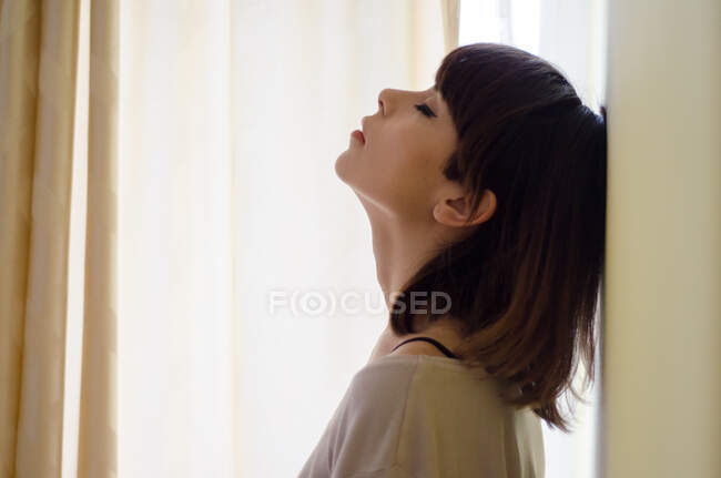 Portrait of a woman with head back leaning against a wall — Stock Photo