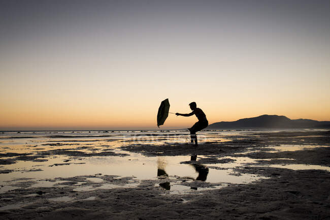 Silhouette dell'uomo che tiene un ombrello, spiaggia di Los Lances, Tarifa, Cadice, Andalusia, Spagna — Foto stock