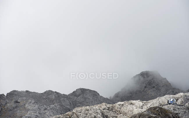 Montanhas rochosas em nuvens de nevoeiro — Fotografia de Stock