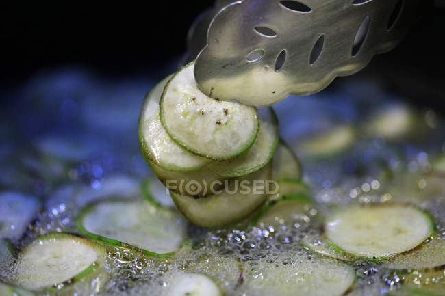 Close-up view of courgettes frying in oil — Stock Photo