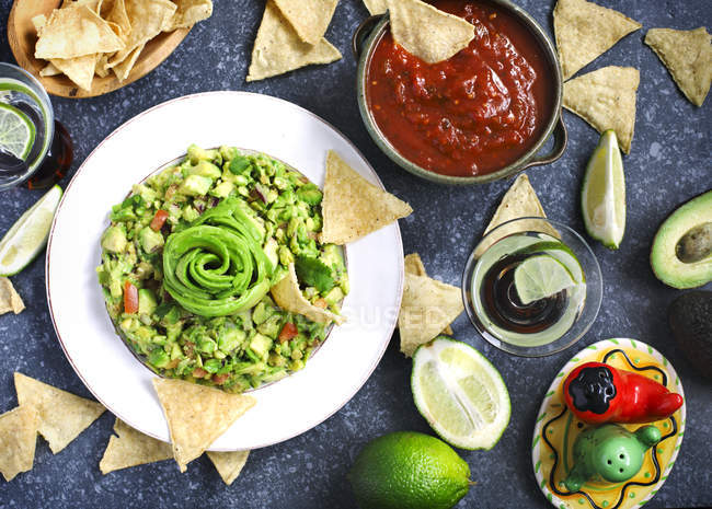 Vista dall'alto di gustosi guacamole, tortilla chips, salsa e lime — Foto stock