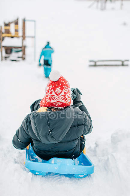 Ragazzo slittino giù per una collina in inverno — Foto stock
