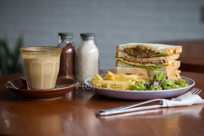 Desayuno club sándwich y café sobre mesa de madera - foto de stock