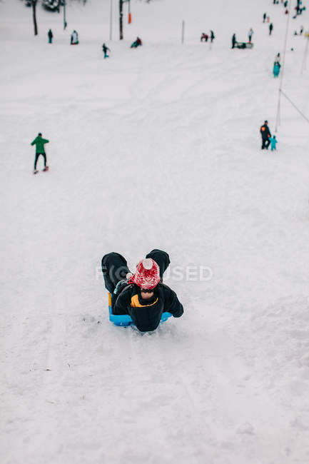 Хлопчик спустився на пагорб взимку — стокове фото