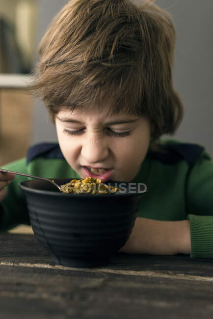 Мальчик сморщивает нос во время обеда со шпинатом — стоковое фото