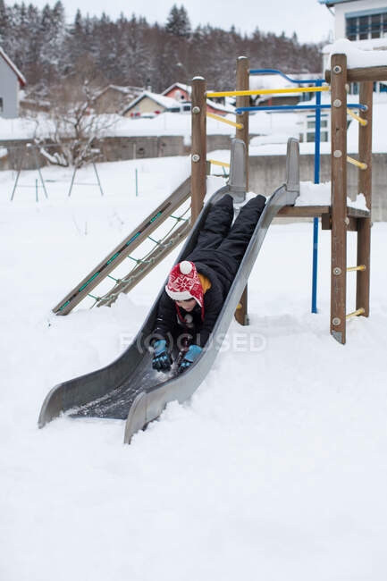 Boy sliding down a slide on his front — Stock Photo
