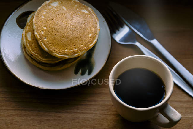 Stack of pancakes with black coffee over table — Stock Photo