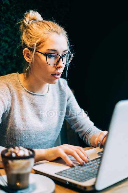 Mujer usando el ordenador portátil en la oficina sobre fondo negro - foto de stock