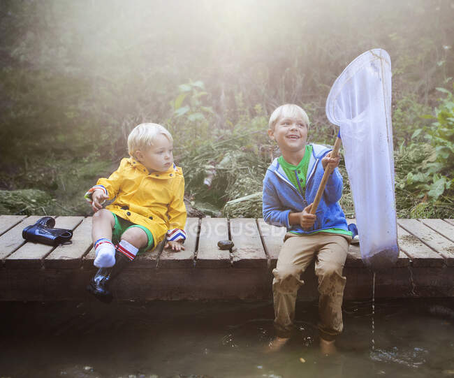 Два мальчика сидят на деревянной причальной рыбалке — стоковое фото