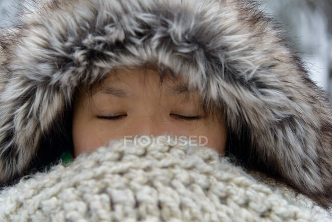 Portrait of a woman wearing a fur hood with eyes closed — Stock Photo