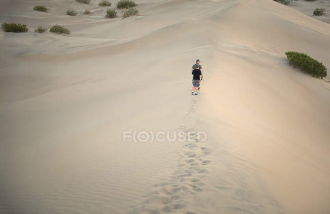 Man and his son walking along sand dunes, Death valley, California, America, USA — Stock Photo