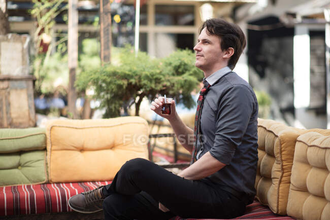 Человек, сидящий в саду с чашкой чая — стоковое фото