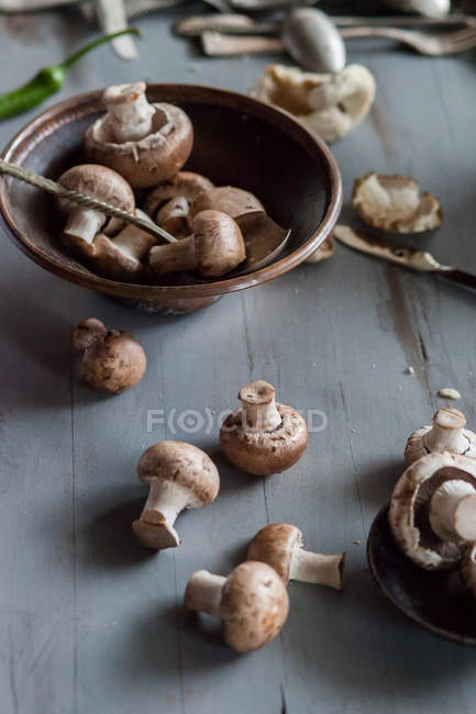 Champignons crus avec bol sur table en bois — Photo de stock