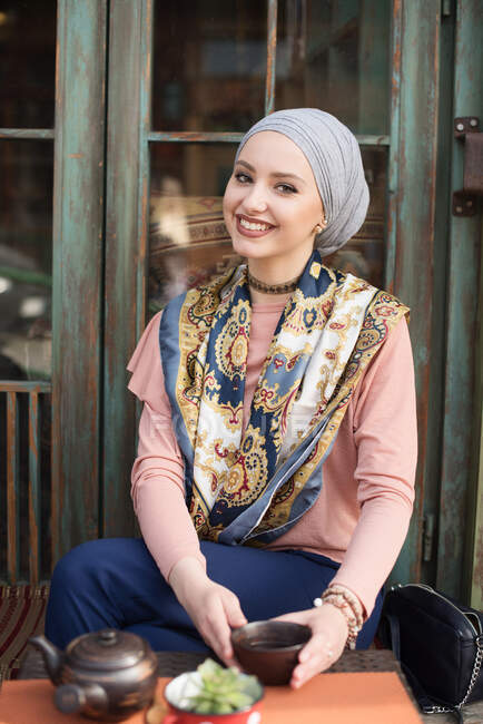 Retrato de uma mulher sorridente em um lenço de cabeça bebendo chá — Fotografia de Stock