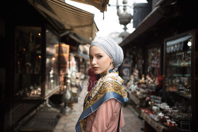 Mujer con un pañuelo en la cabeza de pie en un bazar - foto de stock