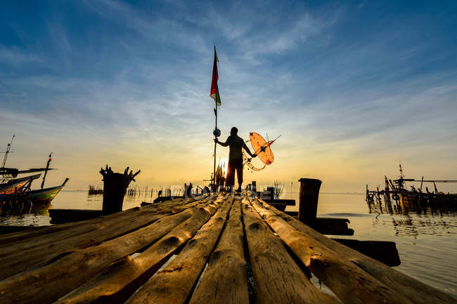 Silhouette d'un pêcheur debout sur une jetée, Thaïlande — Photo de stock