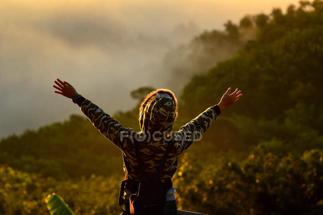 Вид ззаду жінки, що стоїть з руками в повітрі — стокове фото