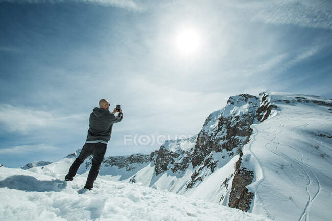 Homme debout sur le sommet de la montagne prendre une photo, chamonix, france — Photo de stock